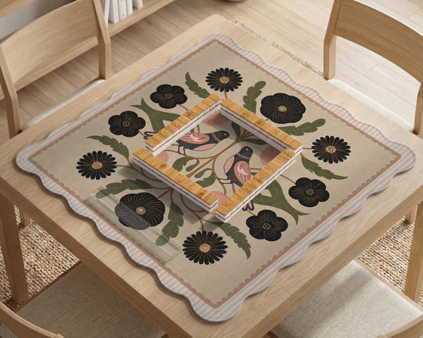 Beige mahjong mat with a botanical floral bird design, blush flowers, olive green leaves, black flower accents, and a warm linen-style background. Scalloped edge option shown.
