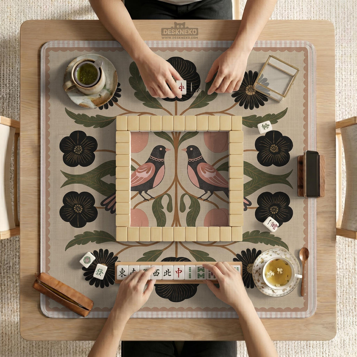Beige mahjong mat with a botanical floral bird design, blush flowers, olive green leaves, black flower accents, and a warm linen-style background. Scalloped edge option shown.