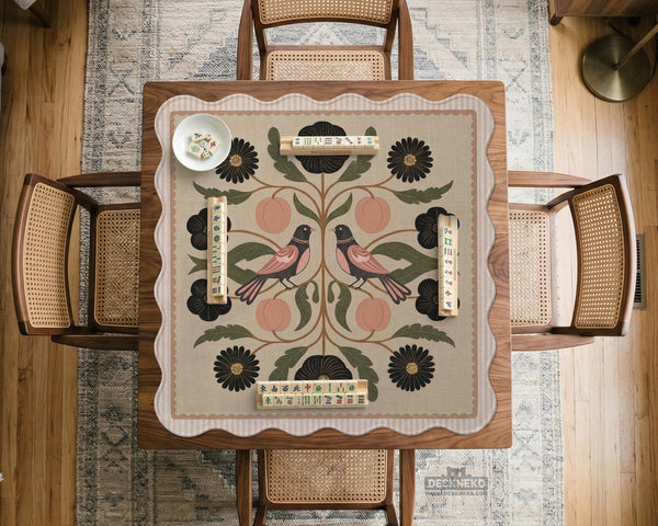 Beige mahjong mat with a botanical floral bird design, blush flowers, olive green leaves, black flower accents, and a warm linen-style background. Scalloped edge option shown.