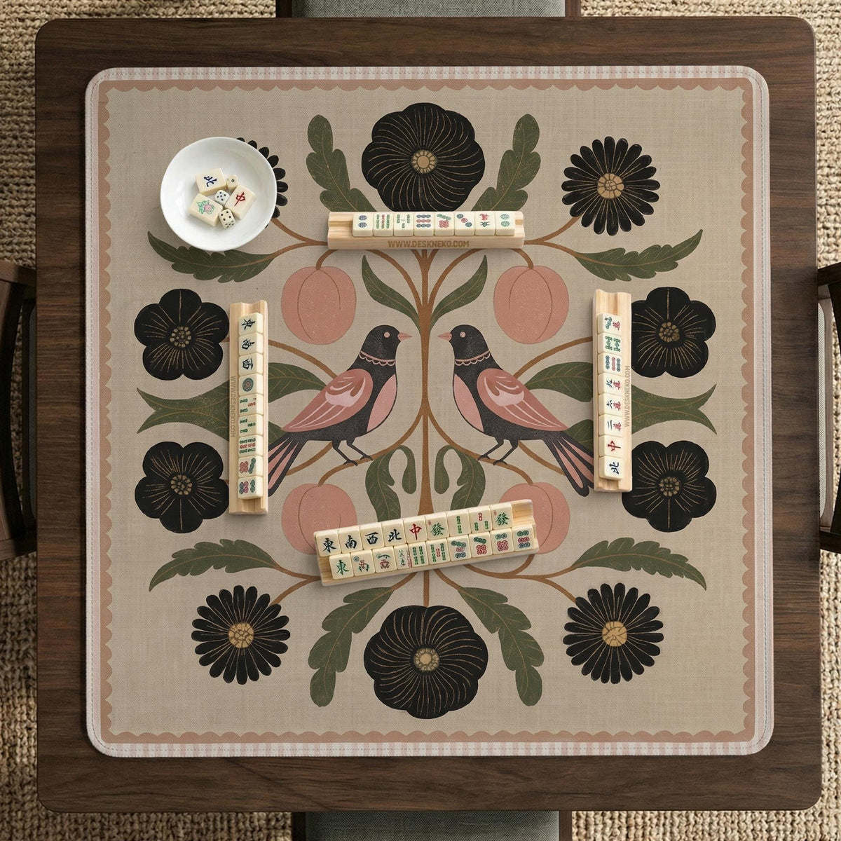 Beige mahjong mat with a botanical floral bird design, blush flowers, olive green leaves, black flower accents, and a warm linen-style background. Scalloped edge option shown.
