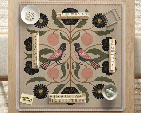 Beige mahjong mat with a botanical floral bird design, blush flowers, olive green leaves, black flower accents, and a warm linen-style background. Scalloped edge option shown.