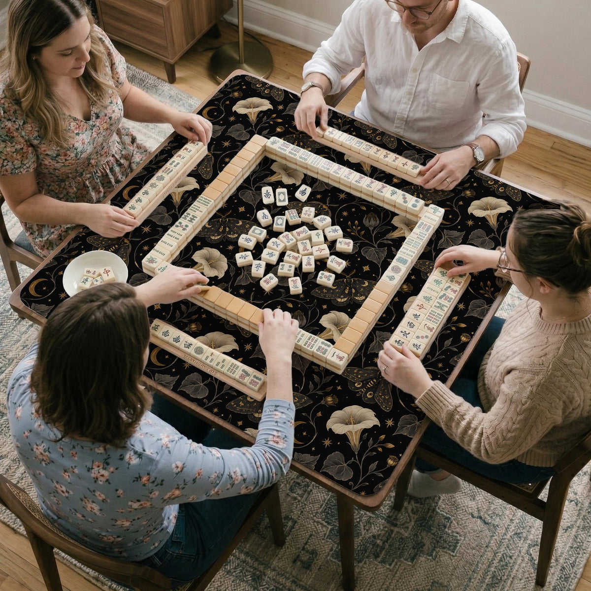 Black square mahjong mat with moths, moonflowers, crescent moons, and scattered stars in a celestial floral pattern.