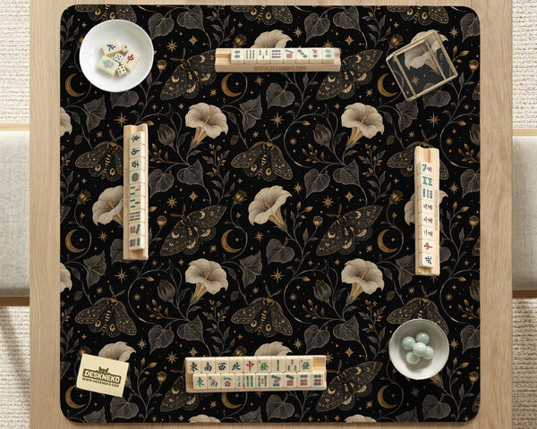 Black square mahjong mat with moths, moonflowers, crescent moons, and scattered stars in a celestial floral pattern.
