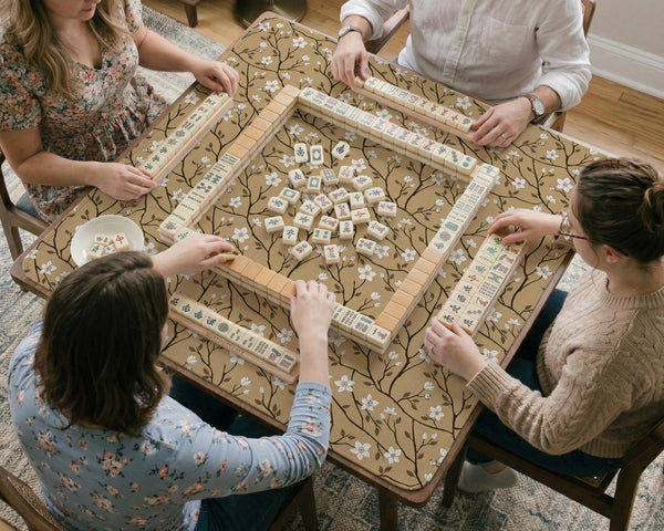Beige mahjong mat with a white blossom branch floral pattern on a neutral background.