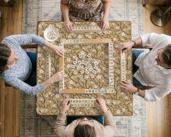Beige mahjong mat with a white blossom branch floral pattern on a neutral background.
