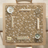 Beige mahjong mat with a white blossom branch floral pattern on a neutral background.
