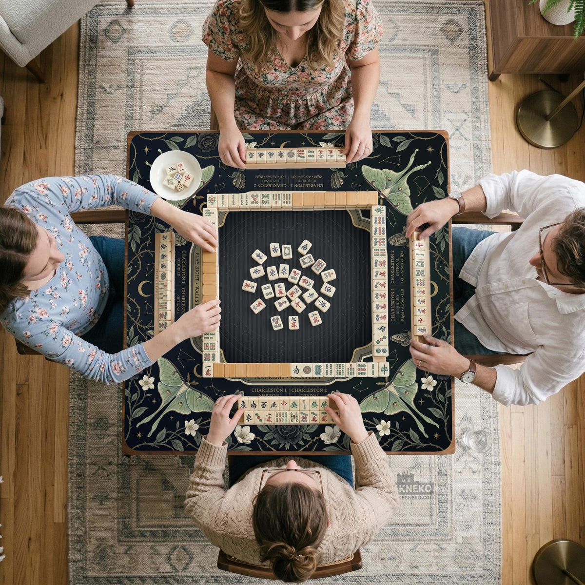 A dark floral mahjong mat with a scalloped edge, moth and flower artwork, and an American Mahjong rules layout on a dark background.
