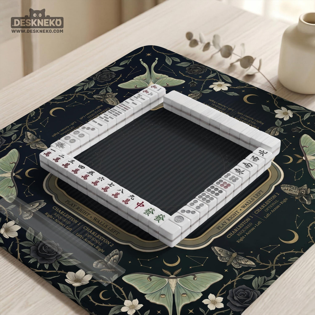 A dark floral mahjong mat with a scalloped edge, moth and flower artwork, and an American Mahjong rules layout on a dark background.