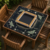 A dark floral mahjong mat with a scalloped edge, moth and flower artwork, and an American Mahjong rules layout on a dark background.