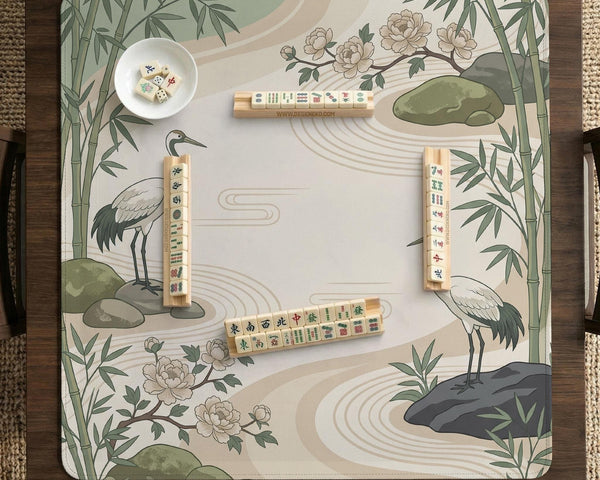 Square mahjong mat with a cream background, sage green cranes, bamboo leaves, peony branches, stones, and thin linework.