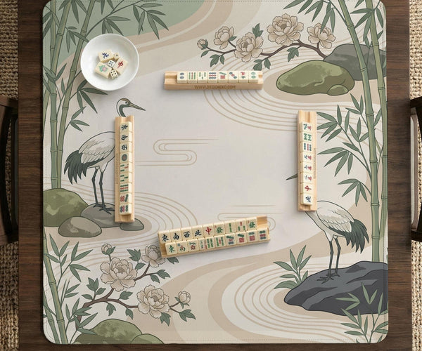 Square mahjong mat with a cream background, sage green cranes, bamboo leaves, peony branches, stones, and thin linework.