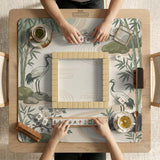 Square mahjong mat with a cream background, sage green cranes, bamboo leaves, peony branches, stones, and thin linework.