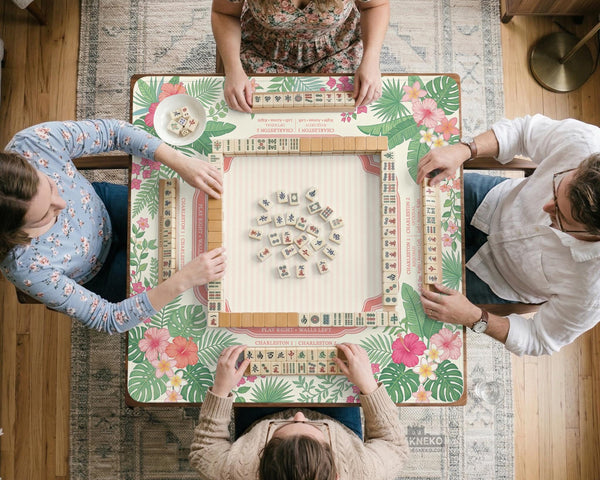 Coral tropical floral mahjong mat with hibiscus flowers, palm leaves, cream sections, and a scalloped edge.