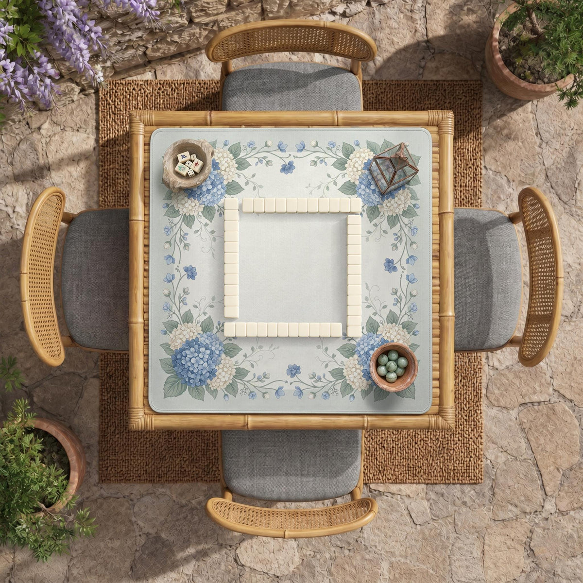 A square blue mahjong mat with hydrangea flowers, cream blossoms, sage leaves, and vines around a plain center play area. The edge is scalloped.