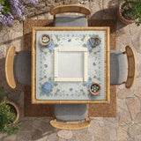 A square blue mahjong mat with hydrangea flowers, cream blossoms, sage leaves, and vines around a plain center play area. The edge is scalloped.