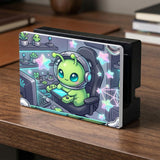 A Switch carrying case design with a cute green alien at a gaming desk, glowing cyan lights, and pastel stars on a dark background.