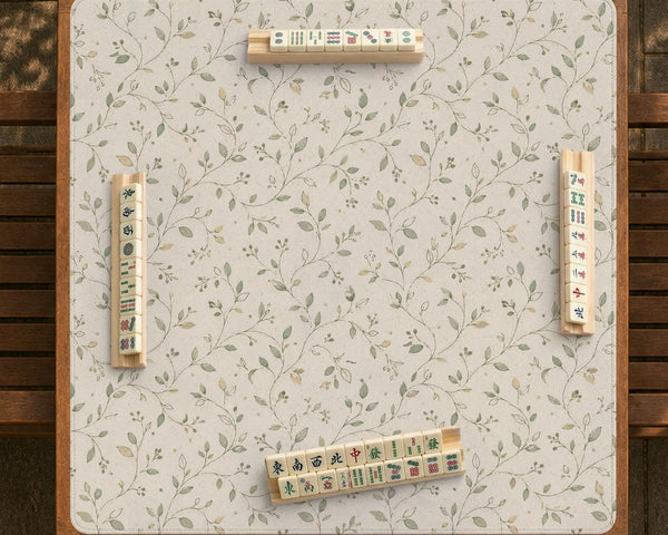 Sage green botanical mahjong mat with a cream background, trailing vines, and muted leaf designs.