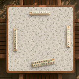 Sage green botanical mahjong mat with a cream background, trailing vines, and muted leaf designs.