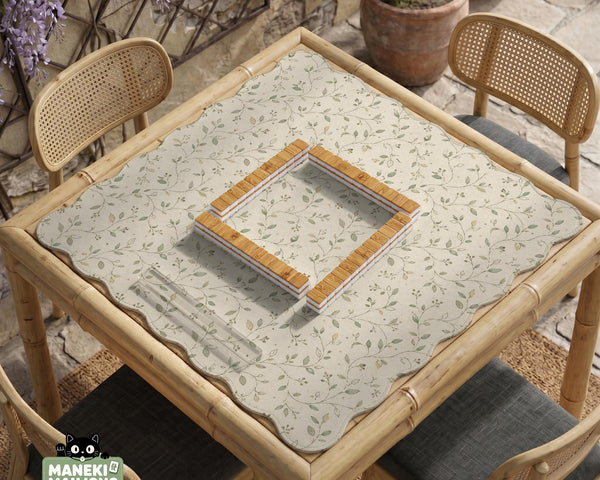 Sage green botanical mahjong mat with a cream background, trailing vines, and muted leaf designs.
