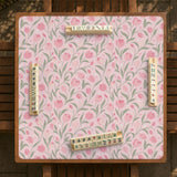 A pink mahjong mat with tulip flowers, sage leaves, and a light pastel background.