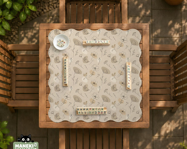 Neutral floral mahjong mat with delicate botanical line art and a scalloped edge on a cream background.