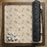 Neutral floral mahjong mat with delicate botanical line art and a scalloped edge on a cream background.