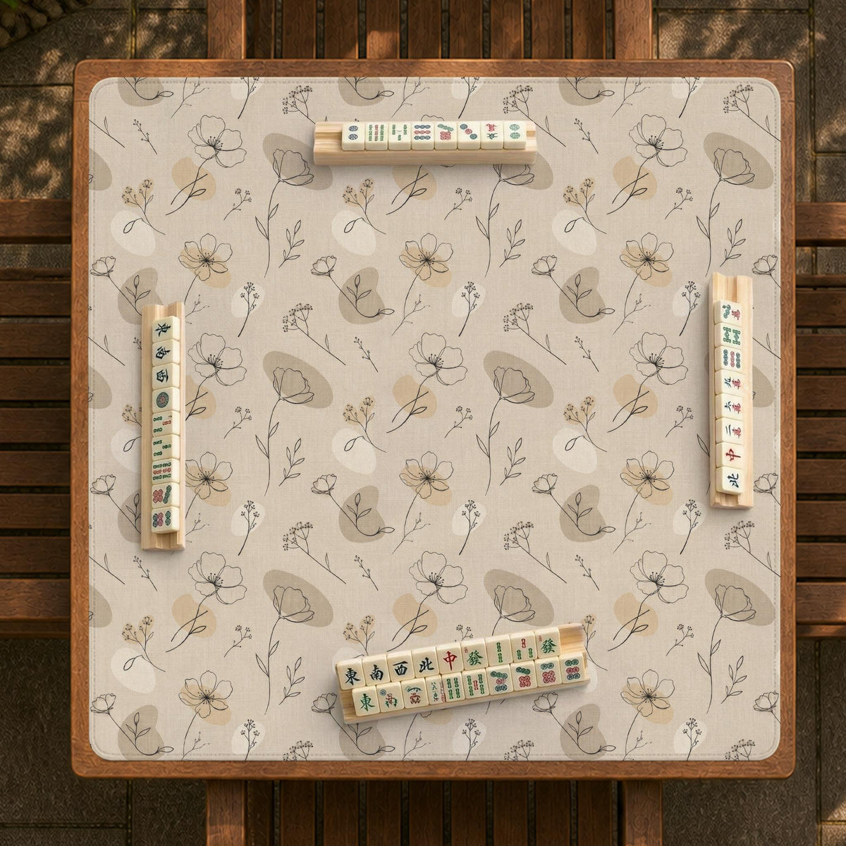 Neutral floral mahjong mat with delicate botanical line art and a scalloped edge on a cream background.