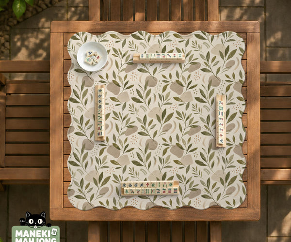 Green botanical mahjong mat with sage leaf and floral design and a scalloped edge.