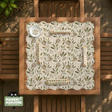 Green botanical mahjong mat with sage leaf and floral design and a scalloped edge.