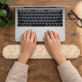 Blush pink floral mouse pad with wrist rest options, shown with peach blossoms, muted leaves, and a warm cream background.