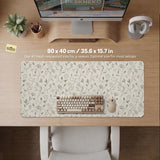 Ivory desk mat with delicate sage and taupe vine and floral artwork on a neutral background.