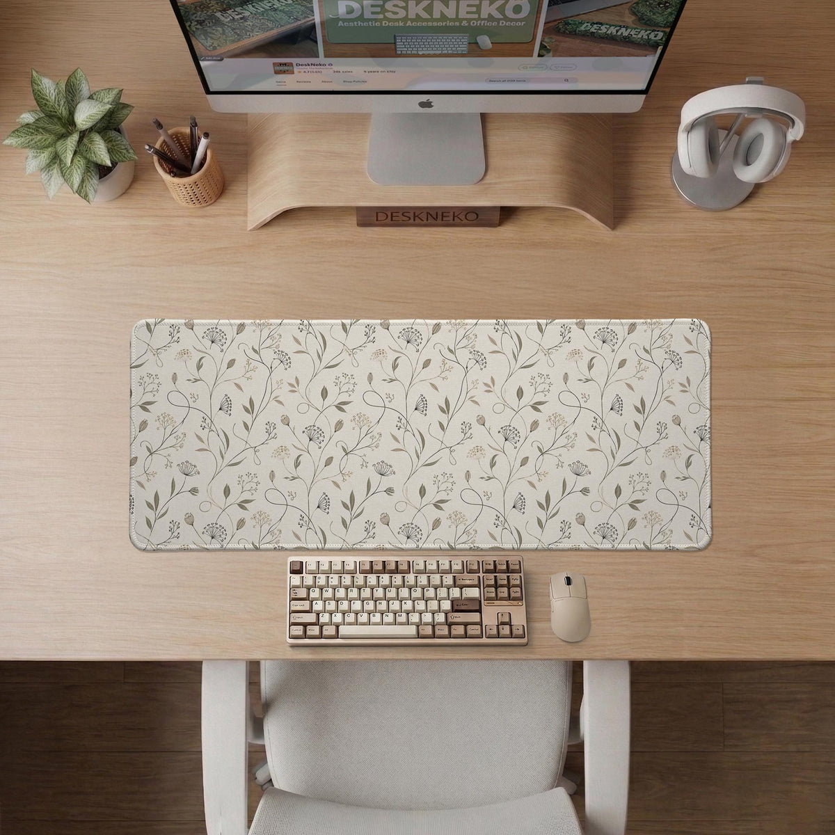 Ivory desk mat with delicate sage and taupe vine and floral artwork on a neutral background.