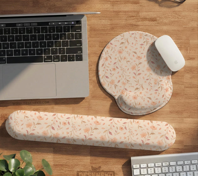 Blush pink floral mouse pad with wrist rest options, shown with peach blossoms, muted leaves, and a warm cream background.