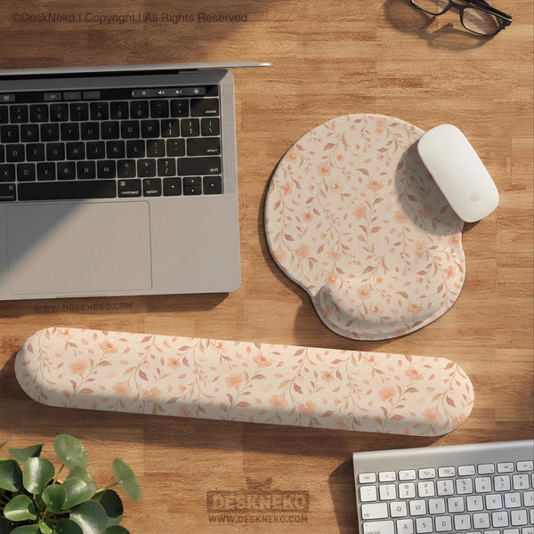 Blush pink floral mouse pad with wrist rest options, shown with peach blossoms, muted leaves, and a warm cream background.