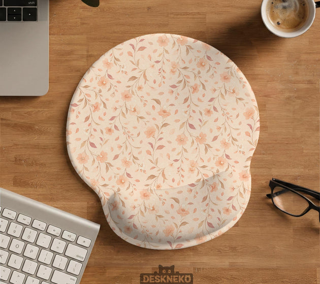 Blush pink floral mouse pad with wrist rest options, shown with peach blossoms, muted leaves, and a warm cream background.