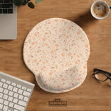 Blush pink floral mouse pad with wrist rest options, shown with peach blossoms, muted leaves, and a warm cream background.