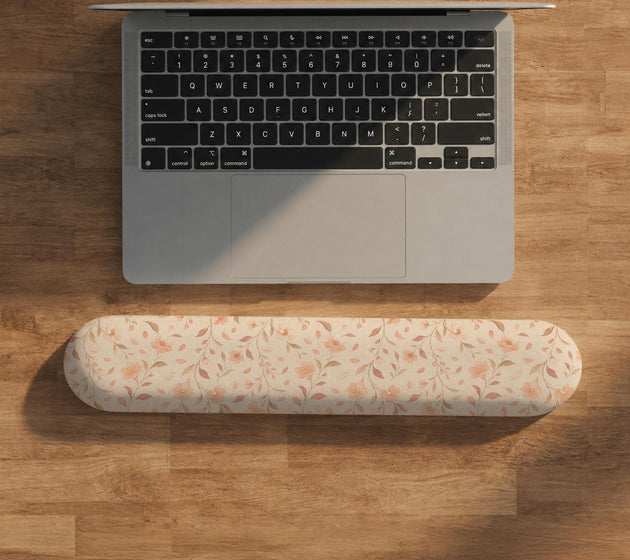Blush pink floral mouse pad with wrist rest options, shown with peach blossoms, muted leaves, and a warm cream background.