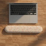Blush pink floral mouse pad with wrist rest options, shown with peach blossoms, muted leaves, and a warm cream background.