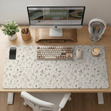 Ivory desk mat with delicate sage and taupe vine and floral artwork on a neutral background.