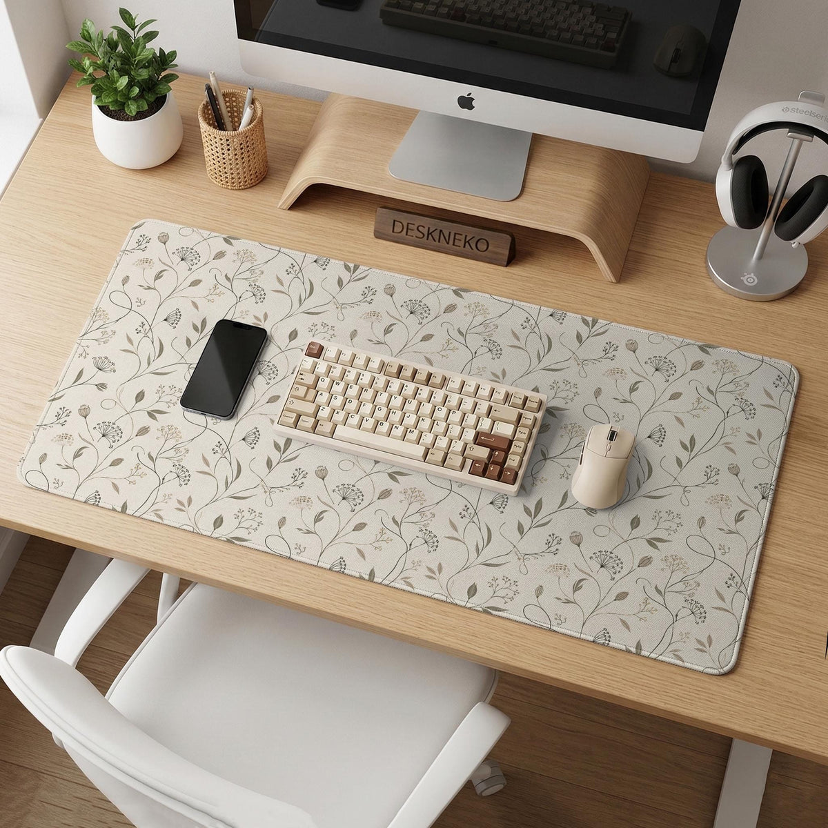 Ivory desk mat with delicate sage and taupe vine and floral artwork on a neutral background.