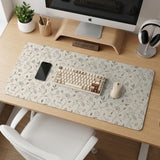 Ivory desk mat with delicate sage and taupe vine and floral artwork on a neutral background.