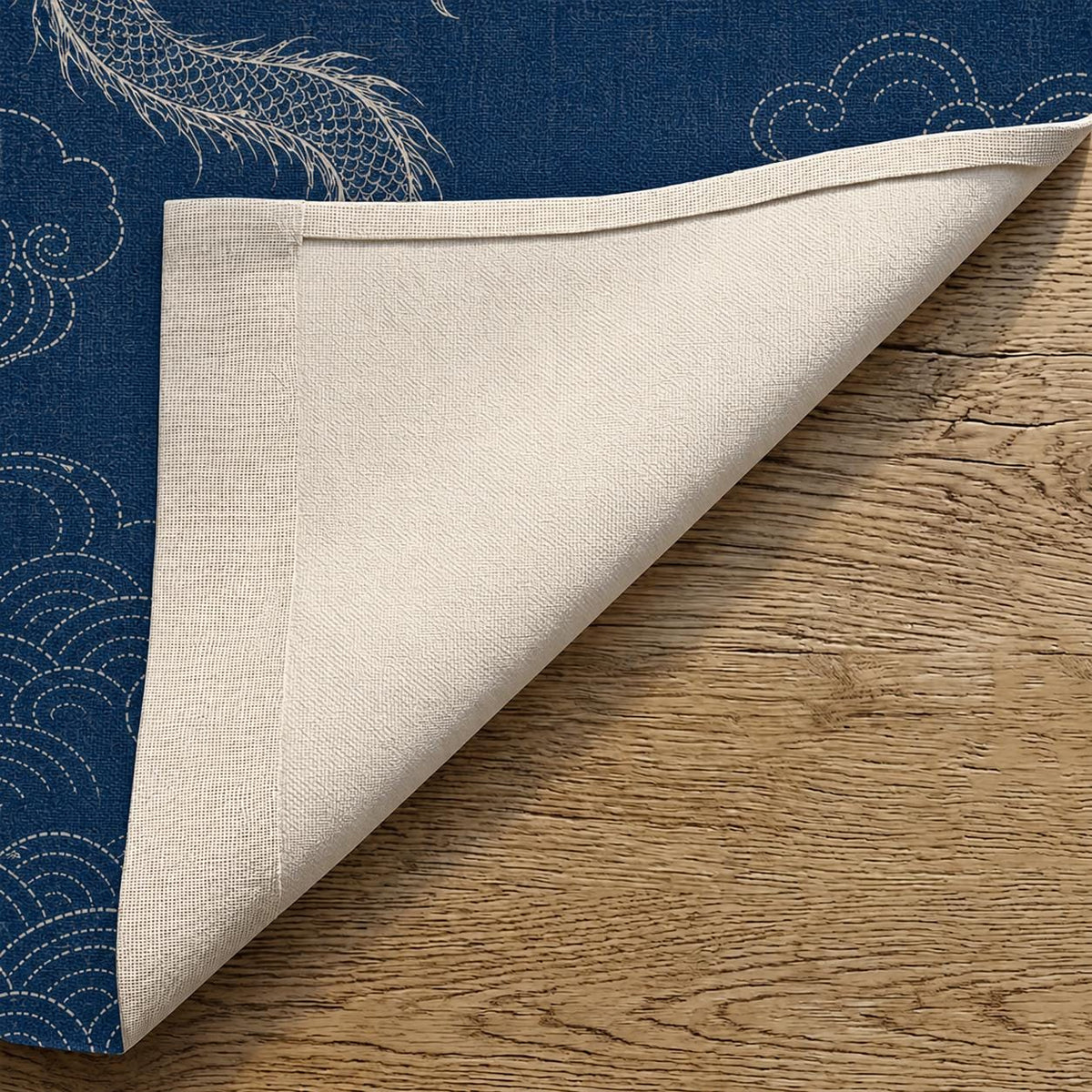 Folded corner of the indigo dragon noren showing the printed front face and plain off-white reverse.