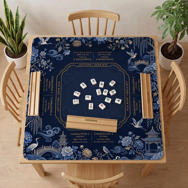Navy mahjong mat with cranes, garden birds, pagodas, and blue and cream floral designs around a framed playing area with a printed Charleston guide.