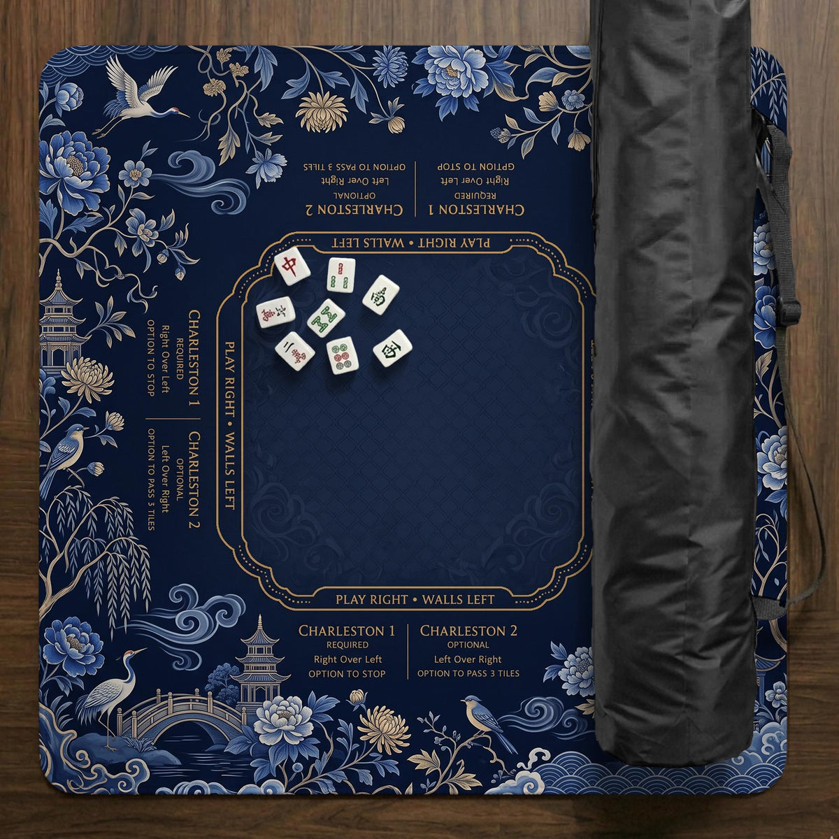 Navy mahjong mat with cranes, garden birds, pagodas, and blue and cream floral designs around a framed playing area with a printed Charleston guide.