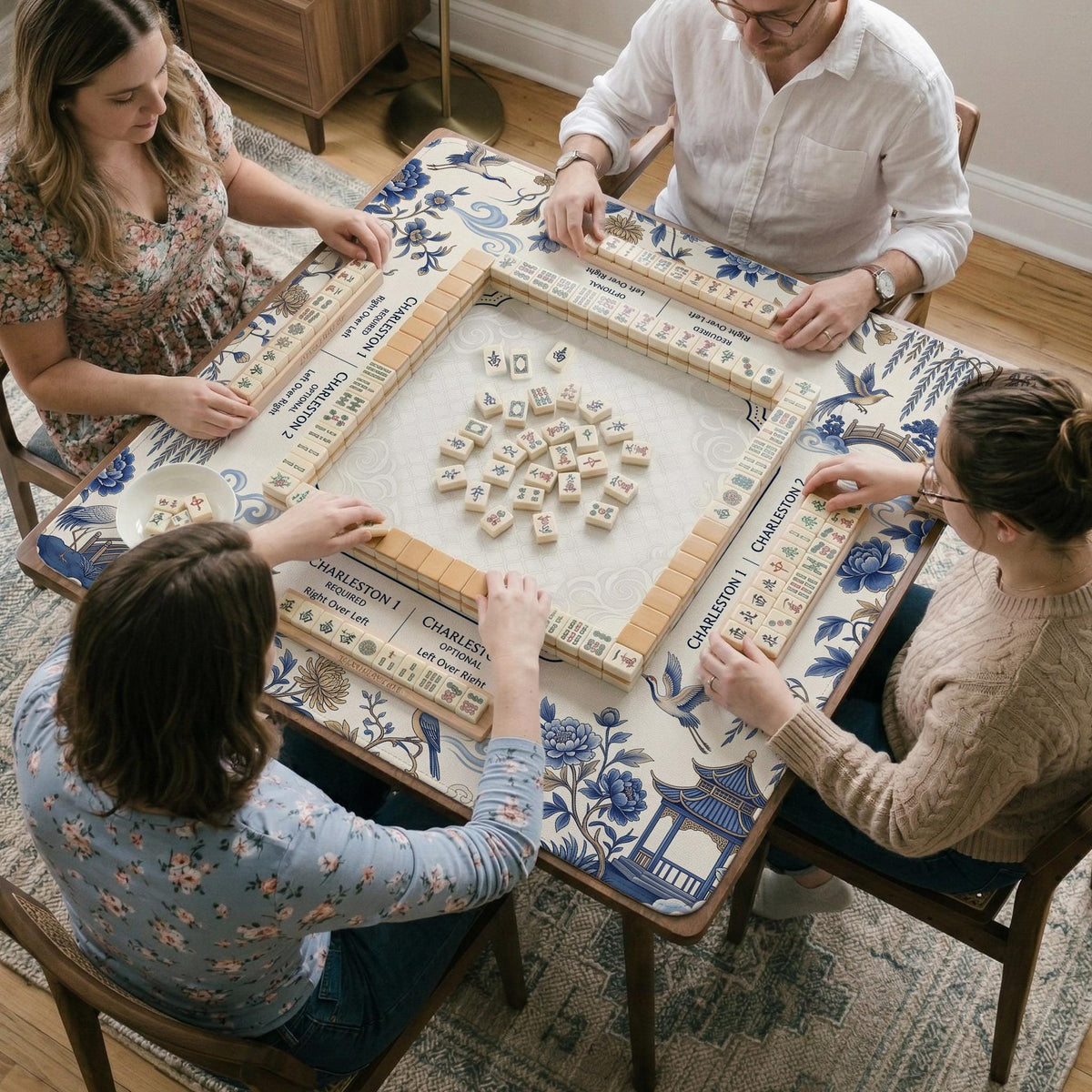 Square ivory mahjong mat with blue cranes, pagodas, flowers, and a blue border around the playing area.
