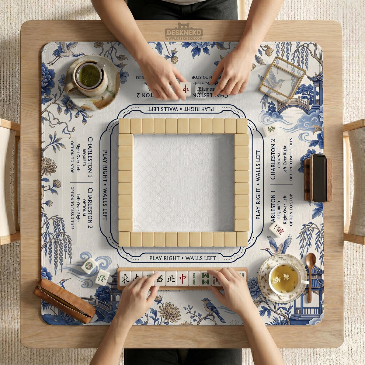 Square ivory mahjong mat with blue cranes, pagodas, flowers, and a blue border around the playing area.
