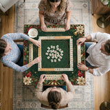 Green mahjong mat with red cardinals, holly berries, cream poinsettias, and gold seasonal details around a printed Charleston guide.