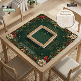 Green mahjong mat with red cardinals, holly berries, cream poinsettias, and gold seasonal details around a printed Charleston guide.