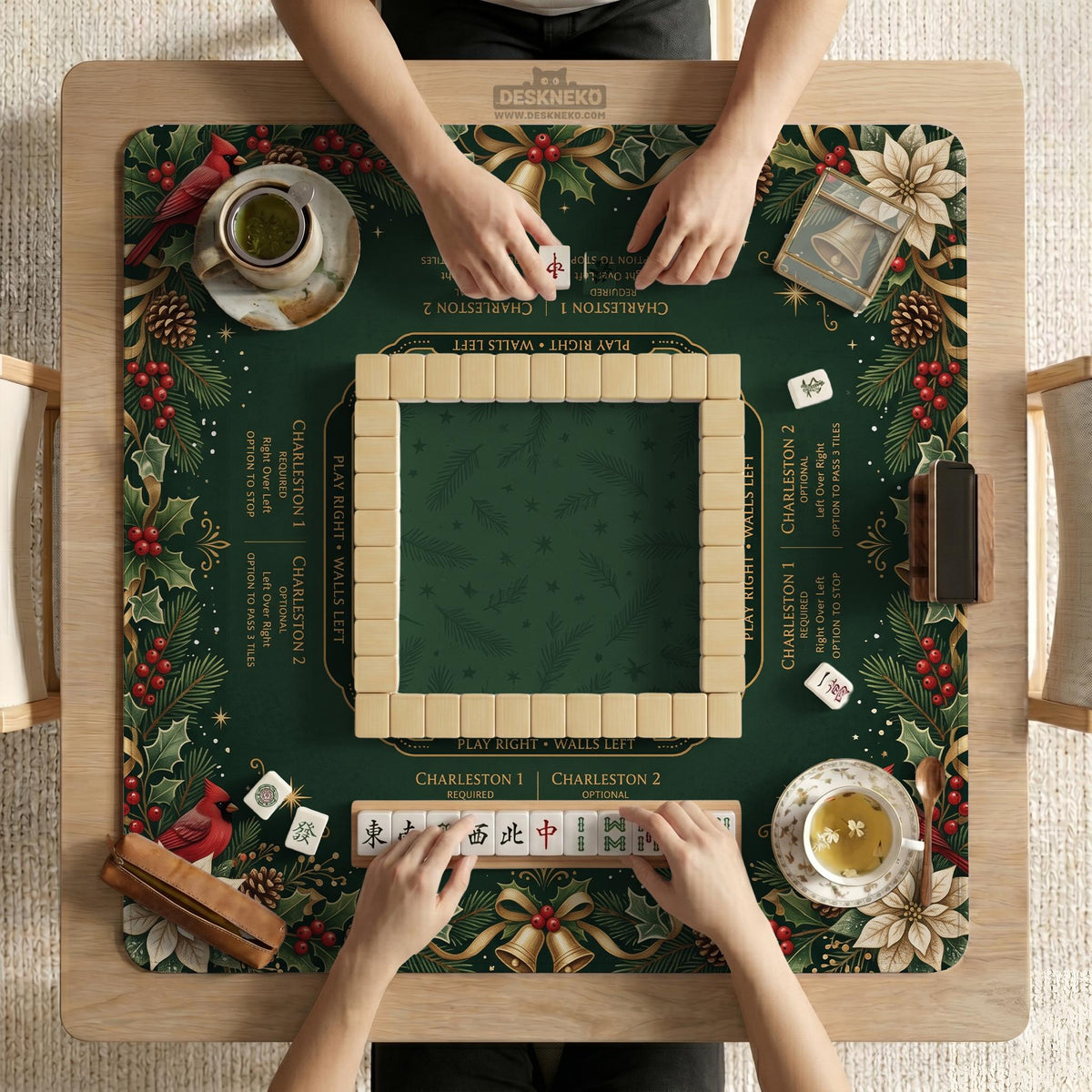 Green mahjong mat with red cardinals, holly berries, cream poinsettias, and gold seasonal details around a printed Charleston guide.