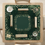 Square mahjong mat with a forest green botanical design, fern leaves, small cream flowers, and a printed Charleston guide around the center area.